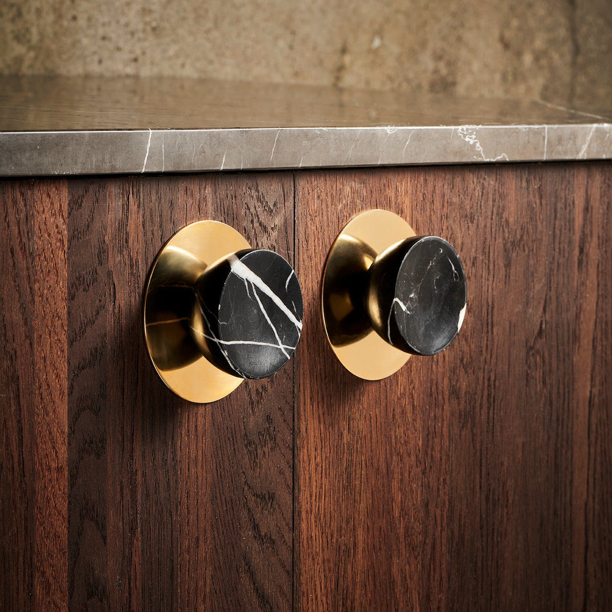 Get a Grip Cabinet Knob pair in Black Marble with polished brass backplates on walnut doors