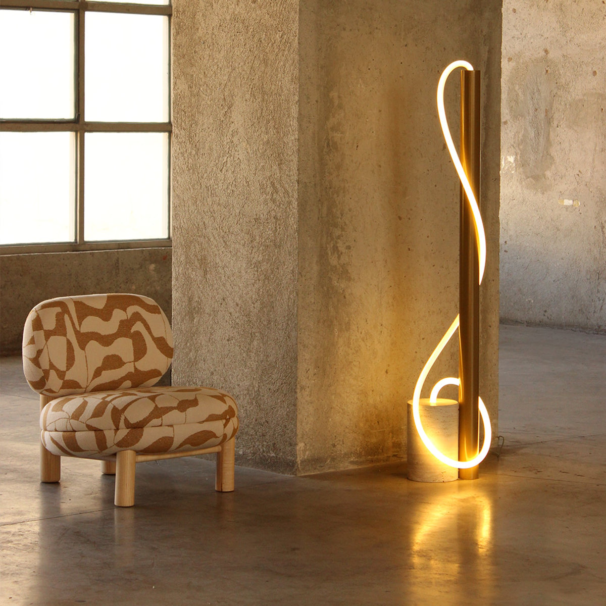 Aimi Lounge Chair in cream and terracotta pattern beside a glowing sculptural floor lamp