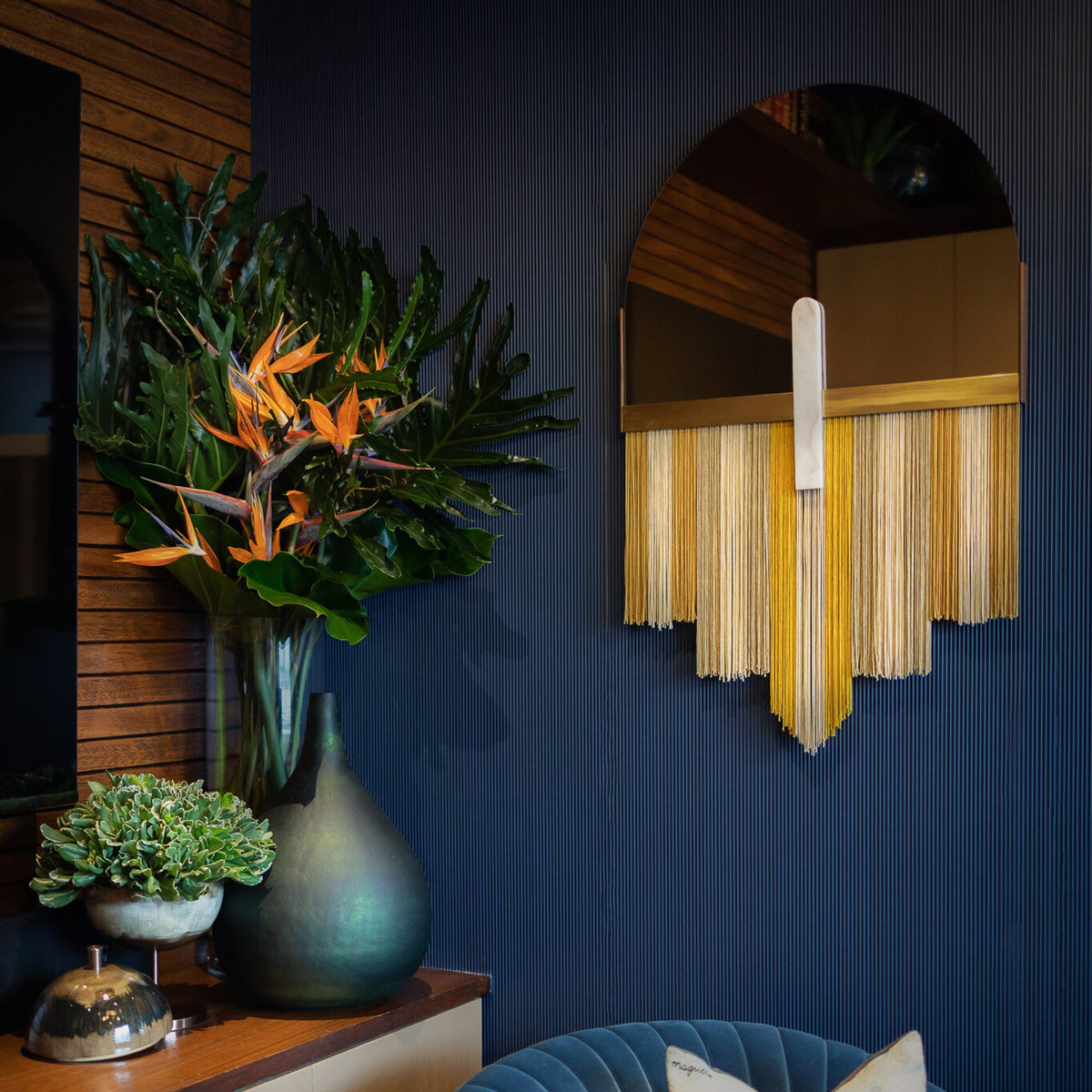 Souk Mirror Yellow on a navy wall beside a bird of paradise arrangement