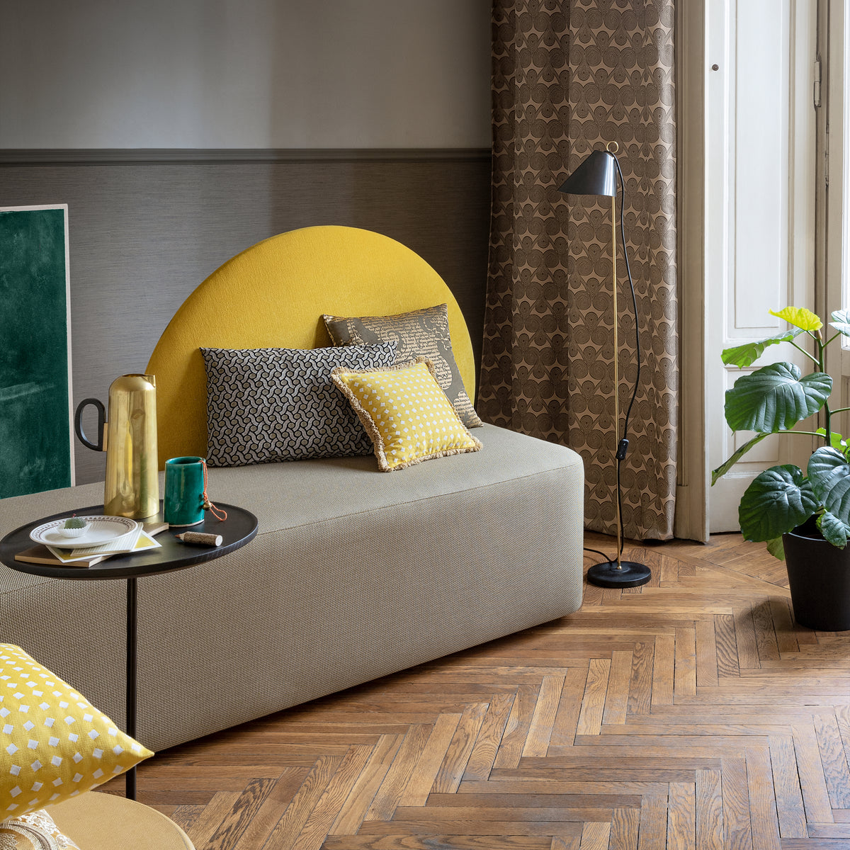 Horizon Sofa with mustard backrest beside a floor lamp and plants