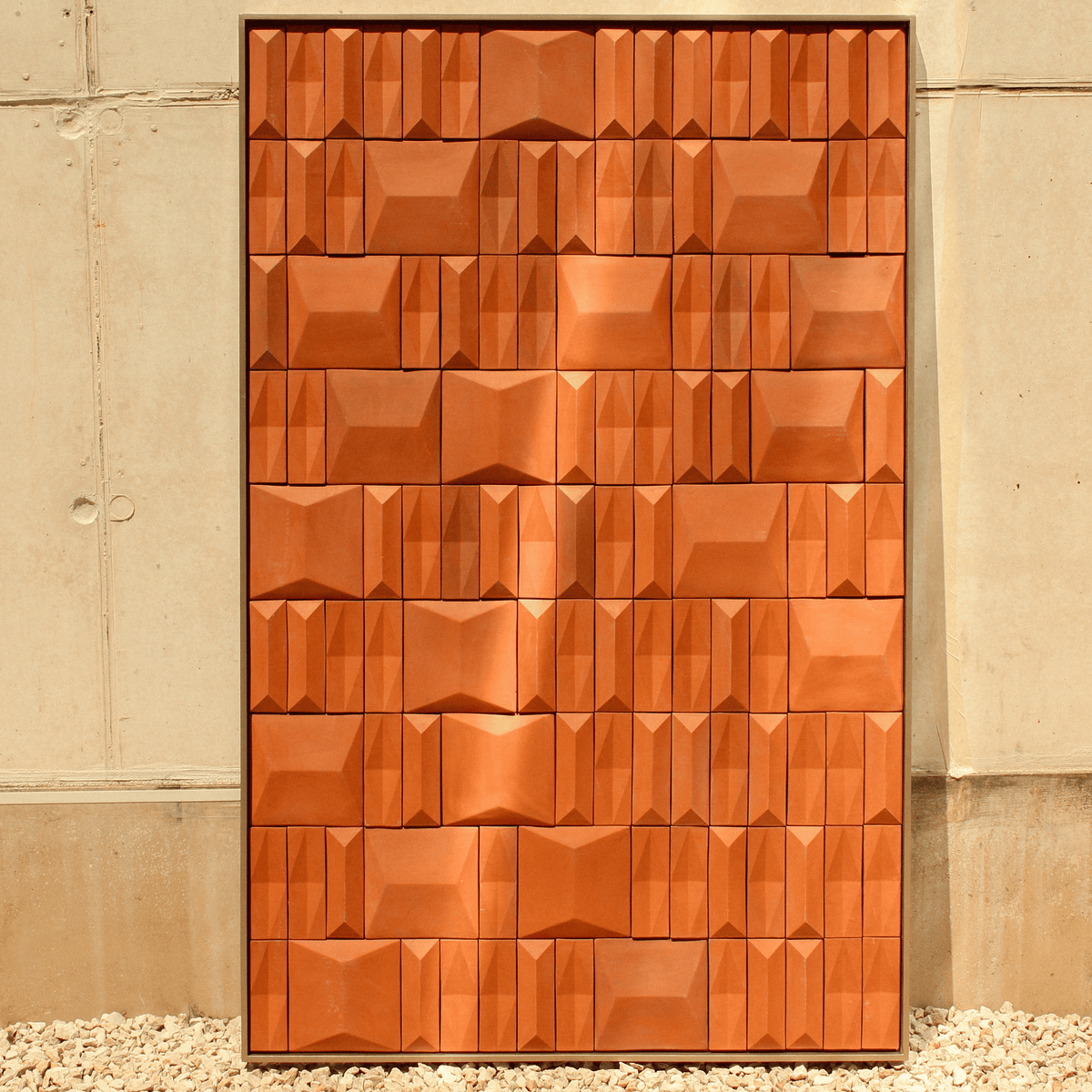 Terra Cota wall art in terracotta relief tiles against a concrete wall