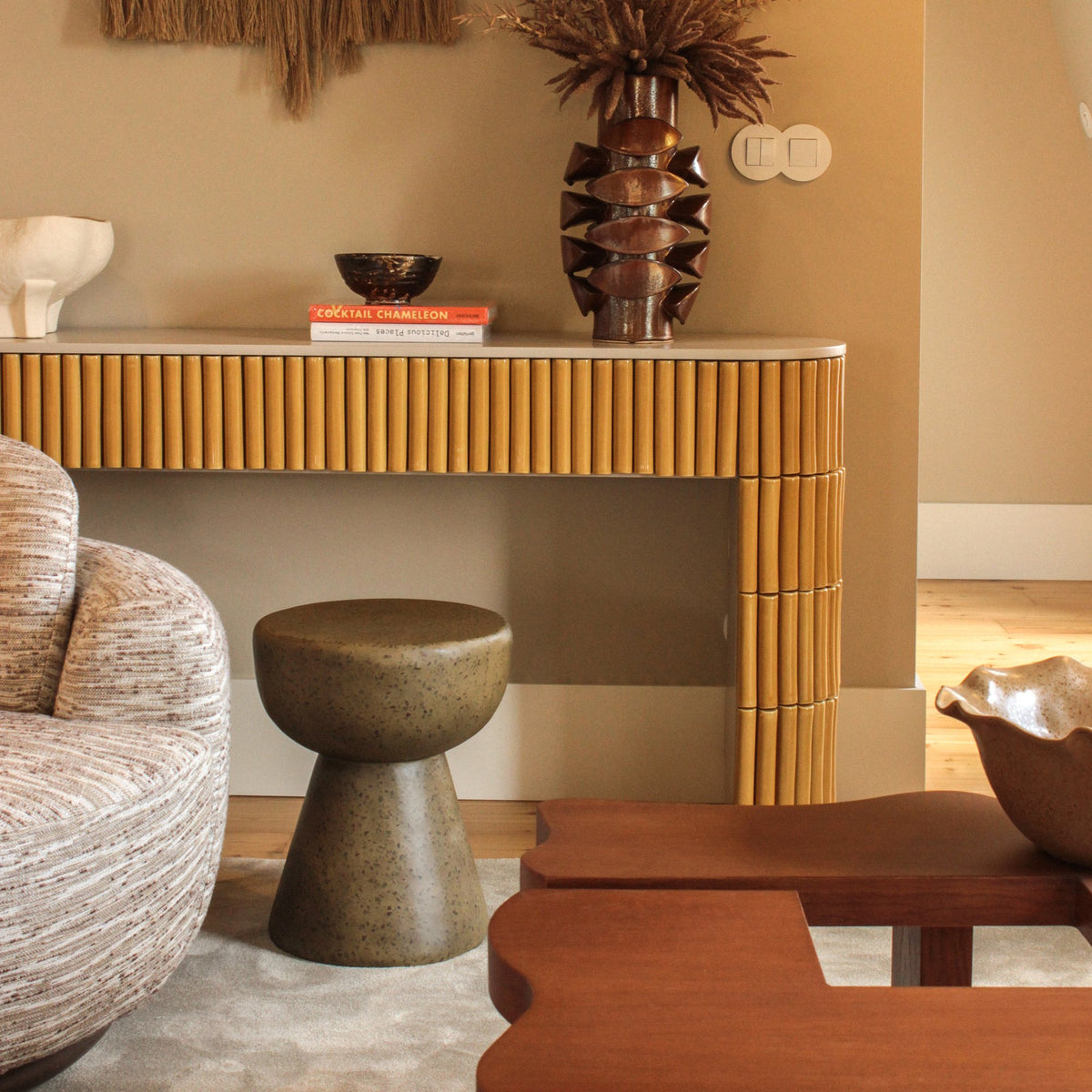 Nouvelle Vague Console Table in Ocre tiles in a living room with a stone stool