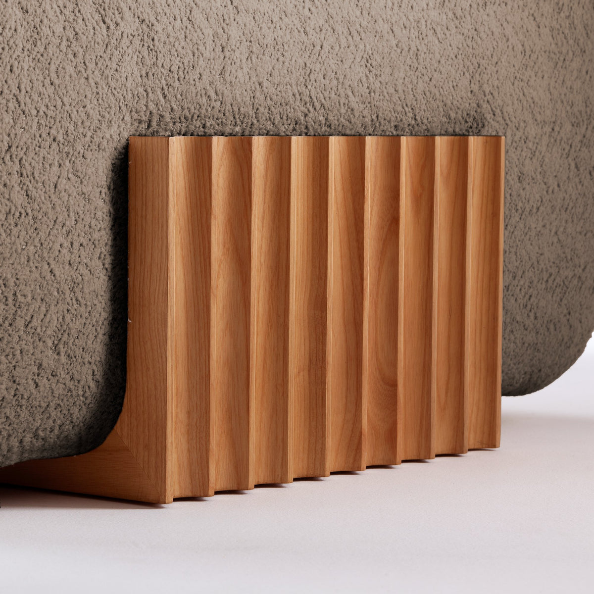 Carmel Ottoman, close-up of the fluted wood base against taupe boucle