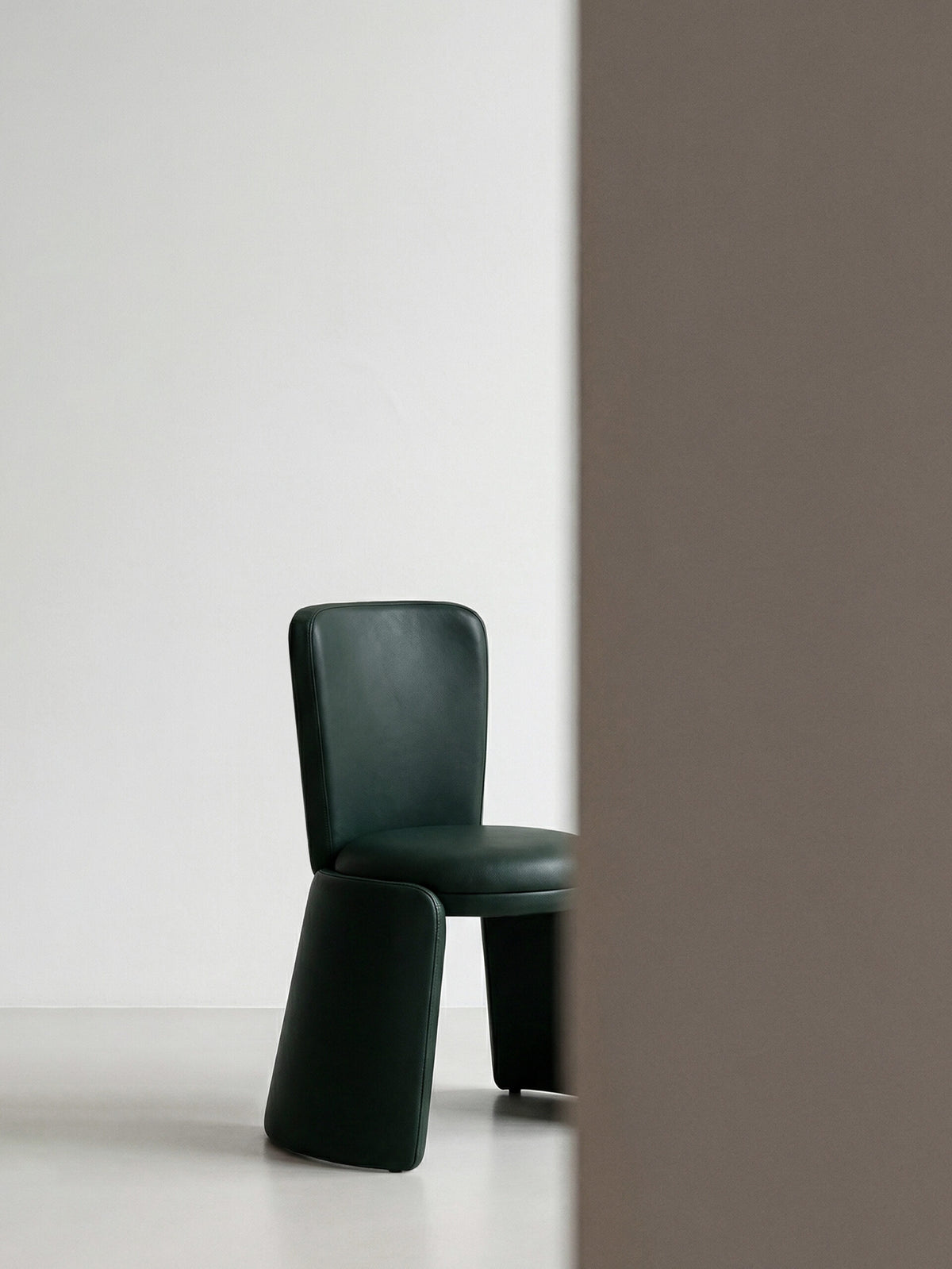 Inge Chair in dark green leather, wider shot in a minimal room