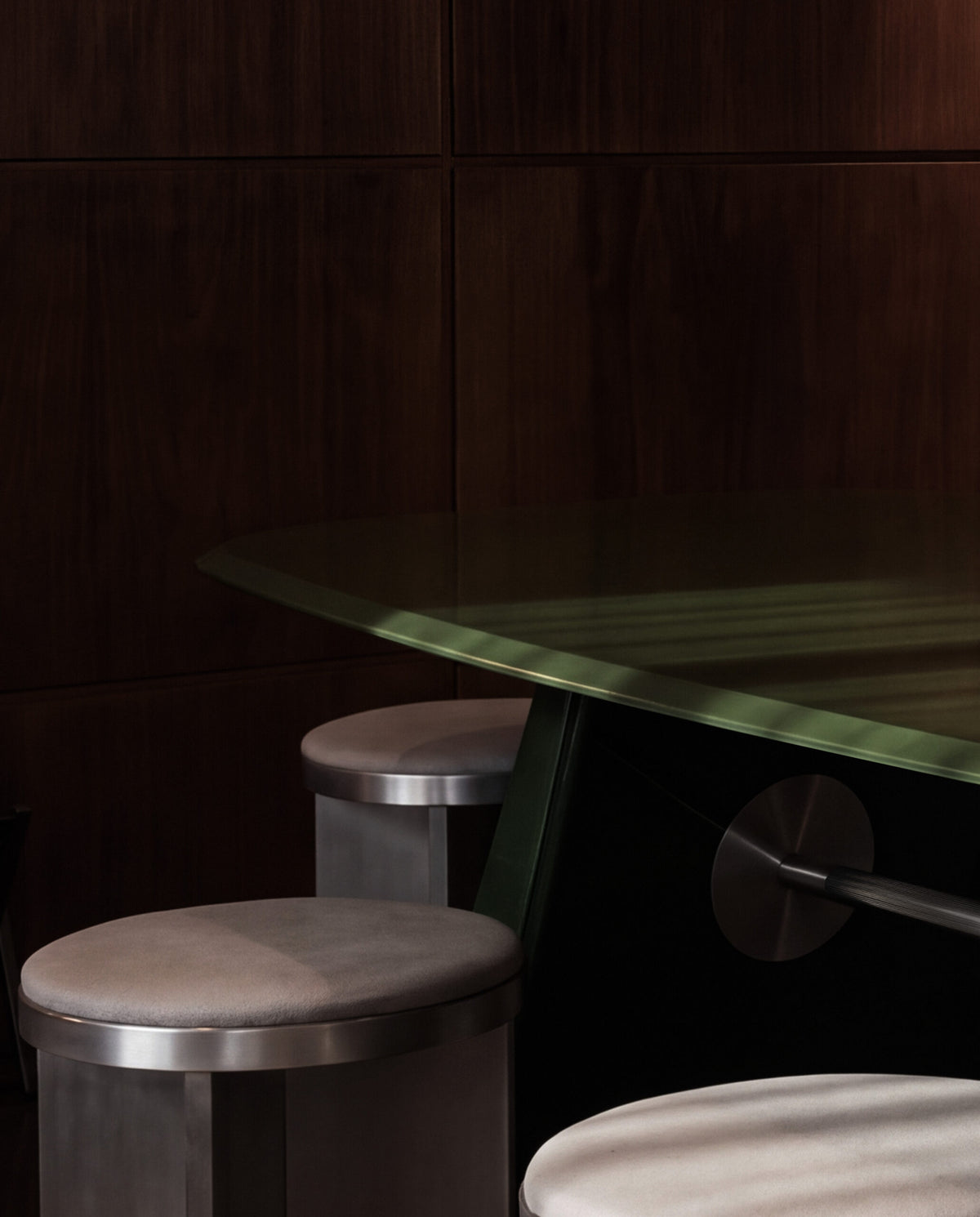 Inge Dining Table with round stools in a dark wood-paneled room