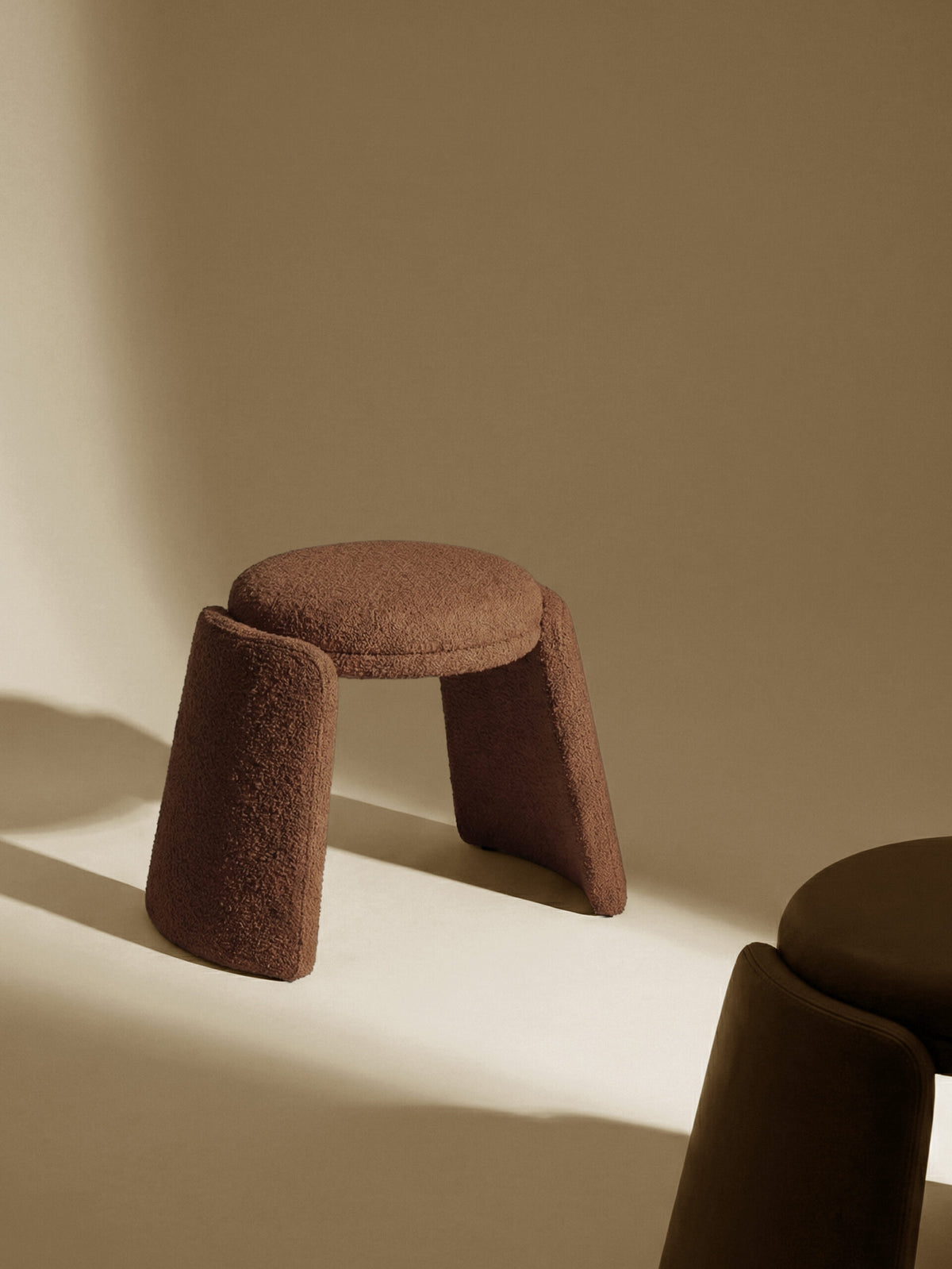 Inge Pouf in brown bouclé against a warm beige wall