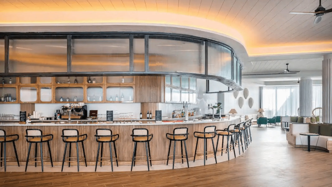 Row of Luc bar chairs along a curved bar in a bright restaurant