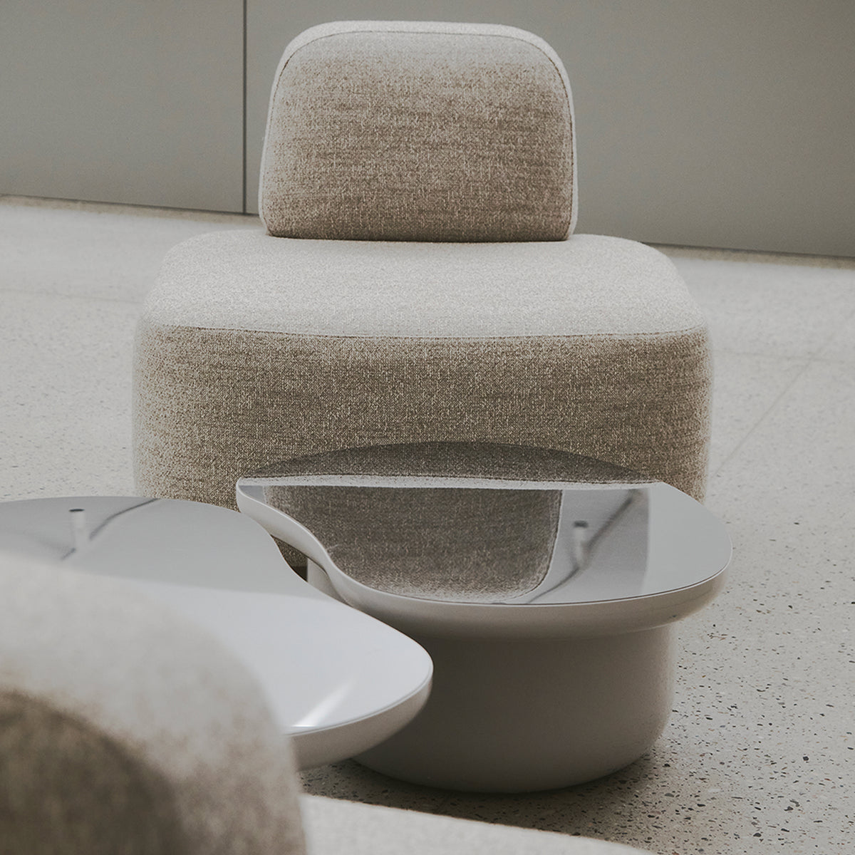 Laghi Coffee Table with mirrored top beside bouclé chairs on terrazzo