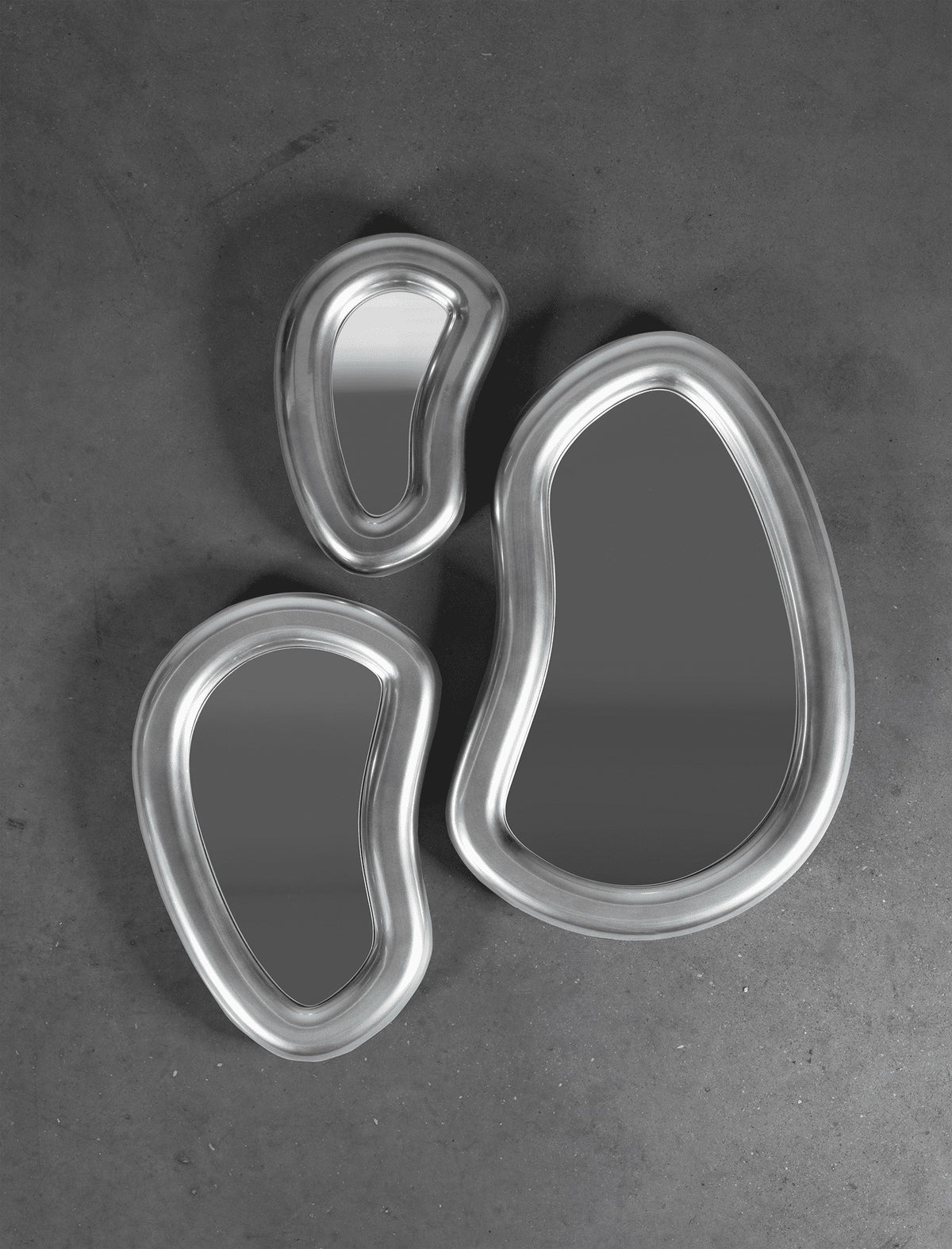 Laghi Mirrors trio in polished silver on a dark concrete wall