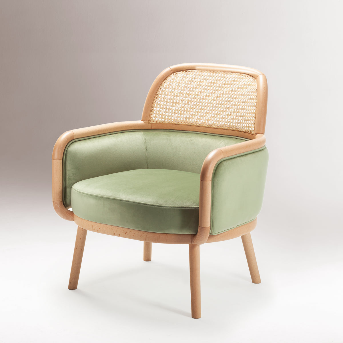 Luc Armchair in sage green velvet on a grey backdrop, three-quarter view