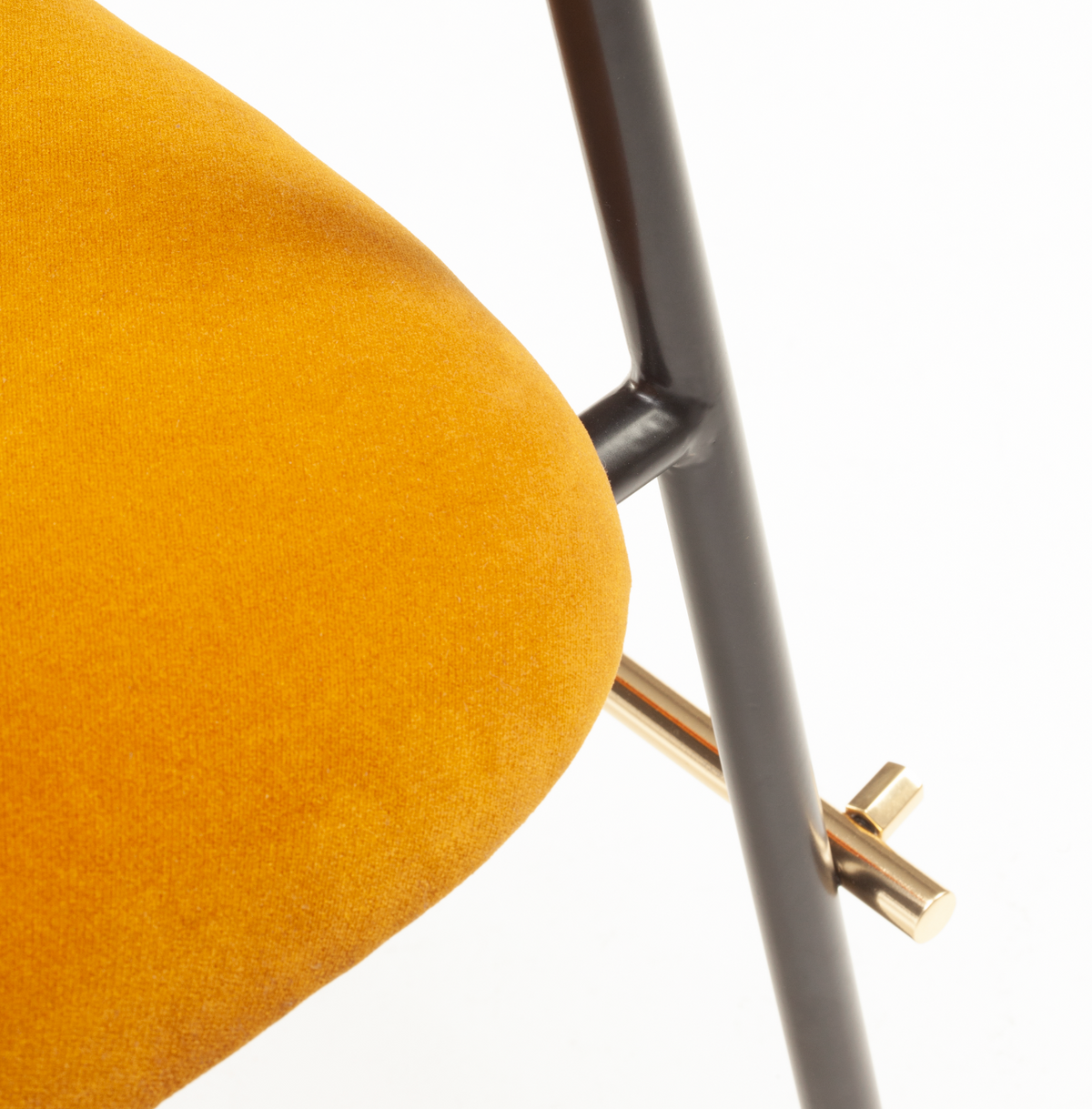 Miami Dining Chair, close-up of the mustard velvet seat edge and brass footrest