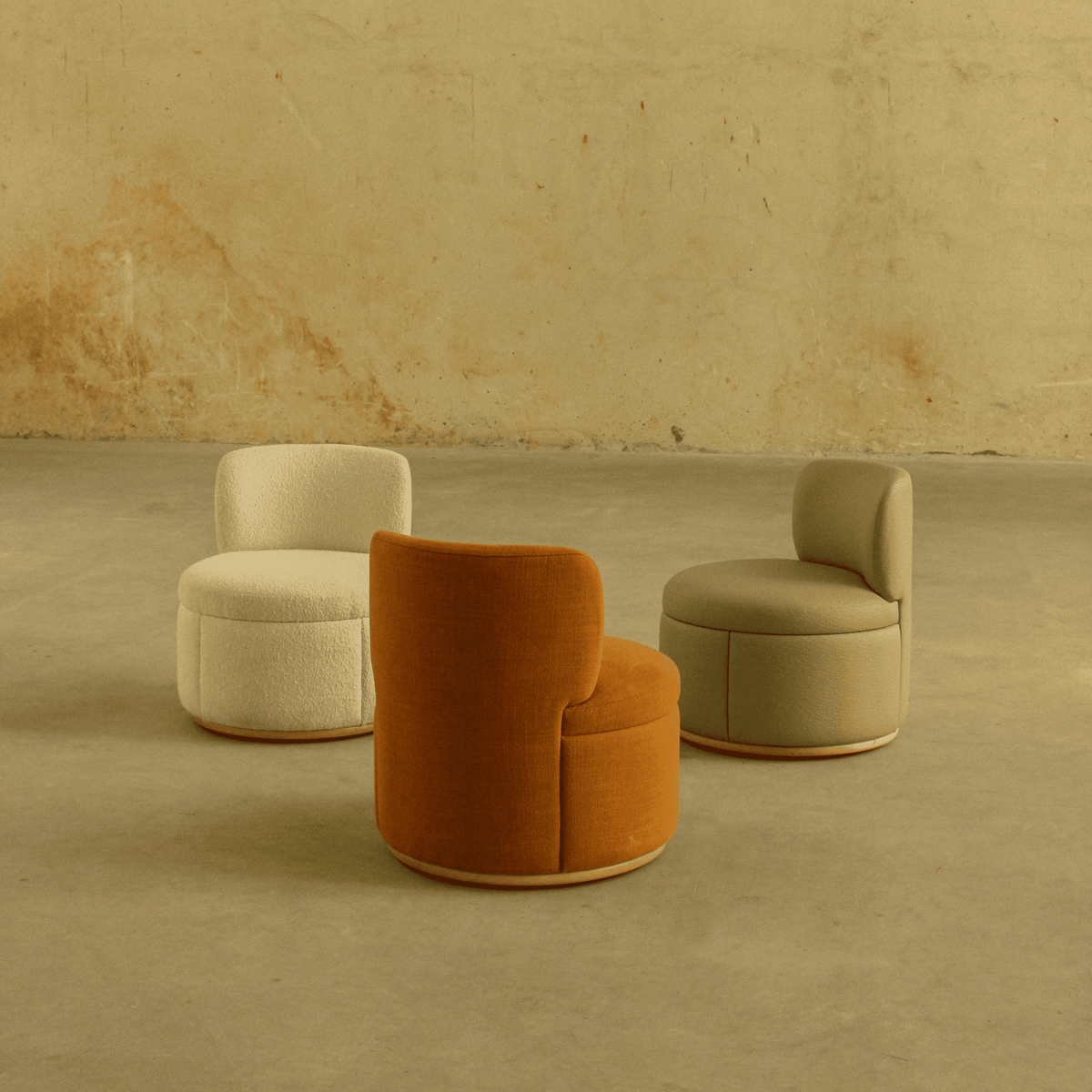 Mimi Swivel Lounge Chairs in cream and rust fabric on a sandy studio floor