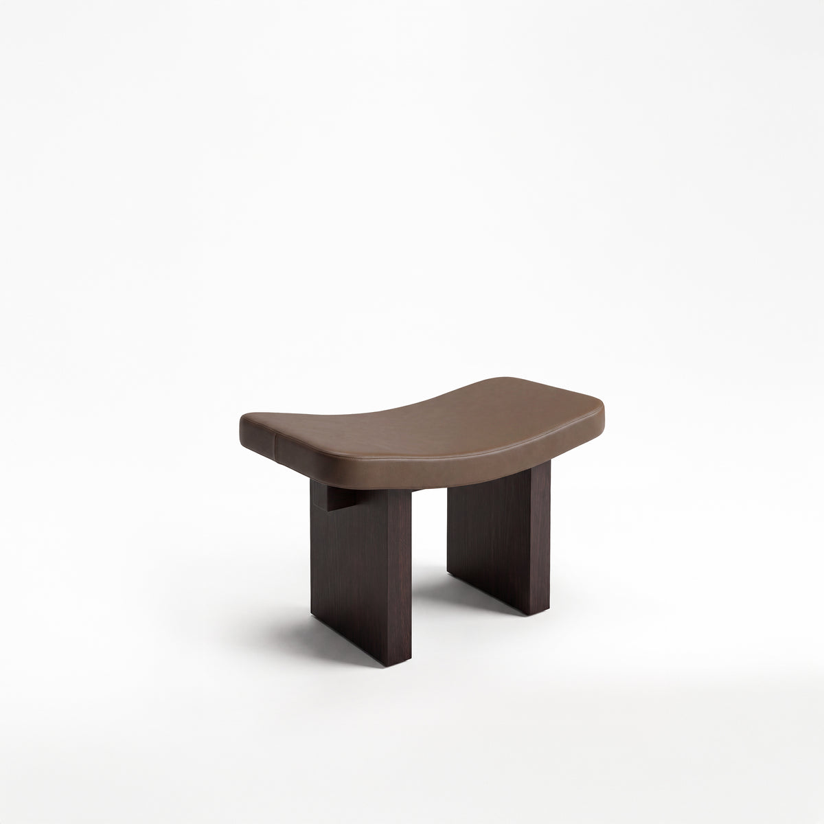 Nara Ottoman in brown leather with dark wood legs, three-quarter view
