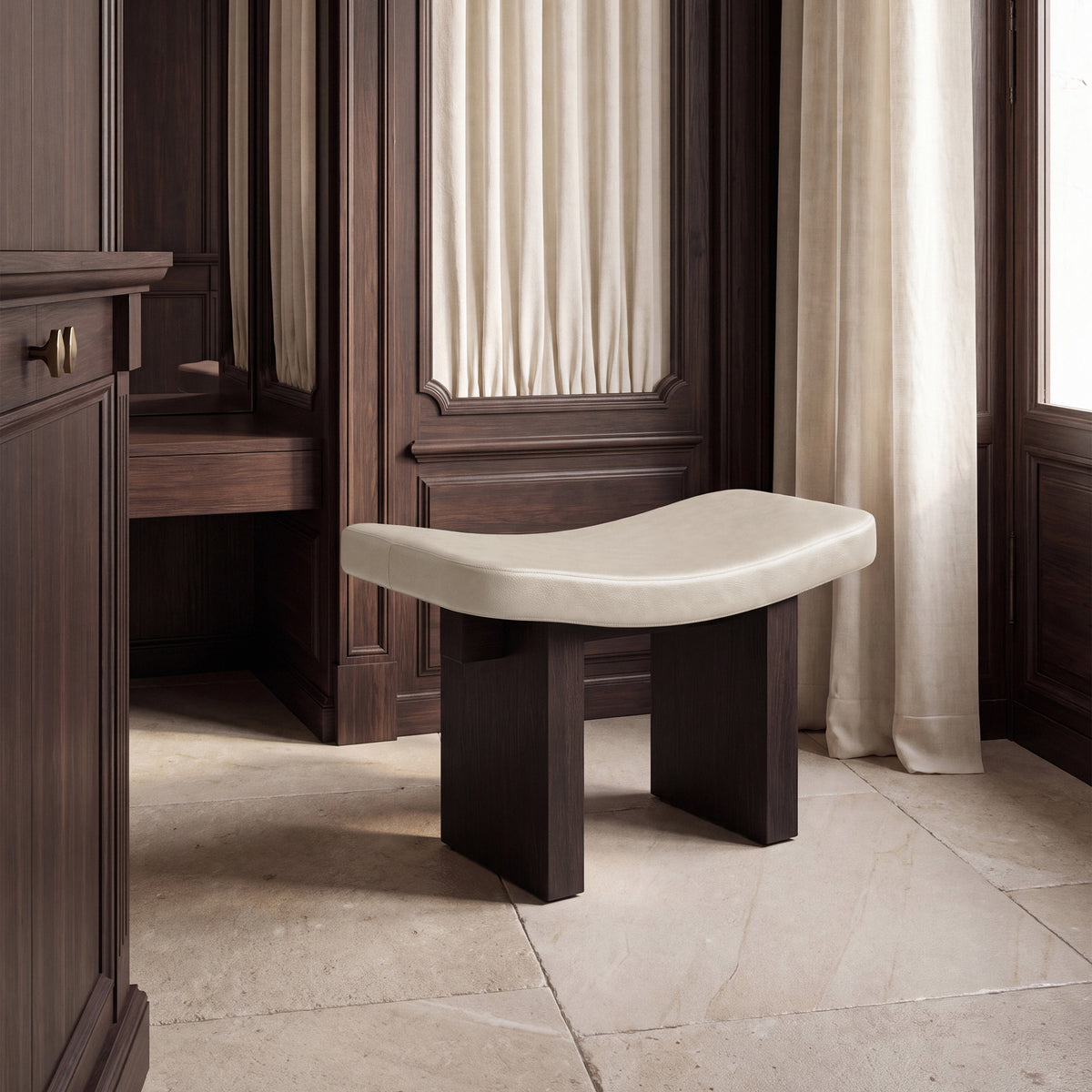 Nara Ottoman in cream on dark wood by a tall window, left view