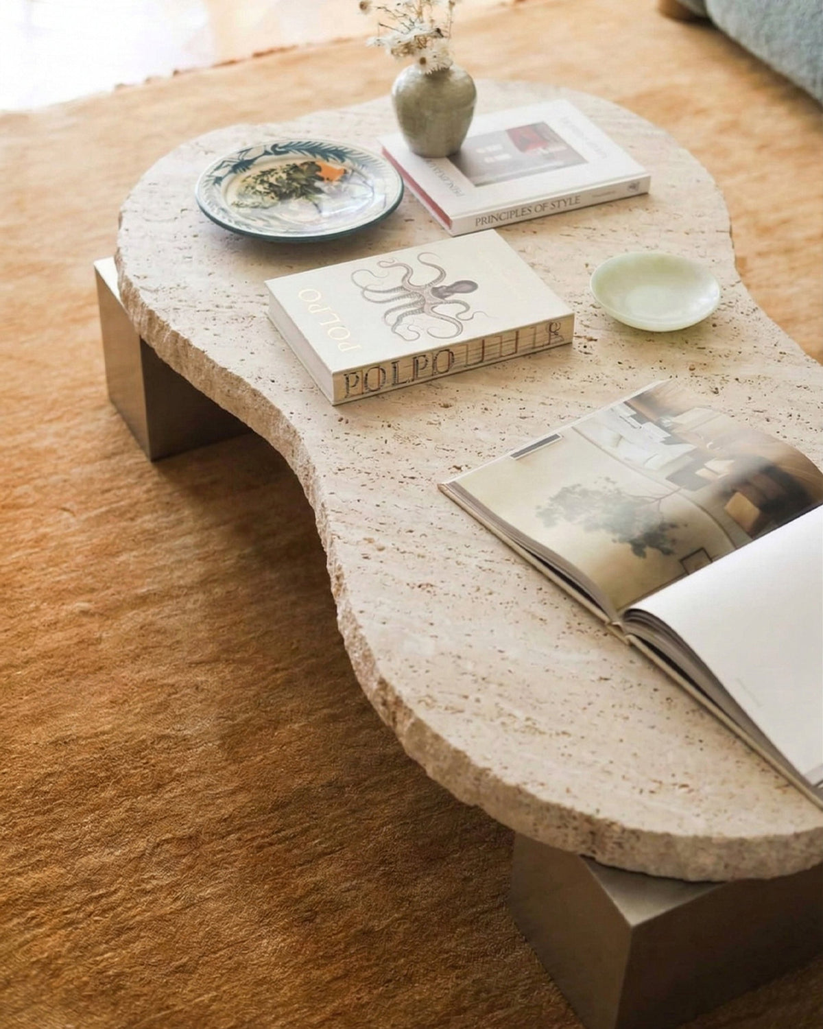 On The Rocks Coffee Table, travertine top, satin nickel base styled with books, by Maison Burgos