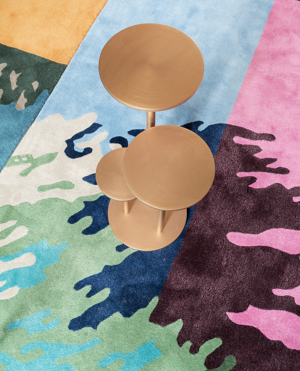 Orion Side Table in Satin Bronze, top view on a colourful rug