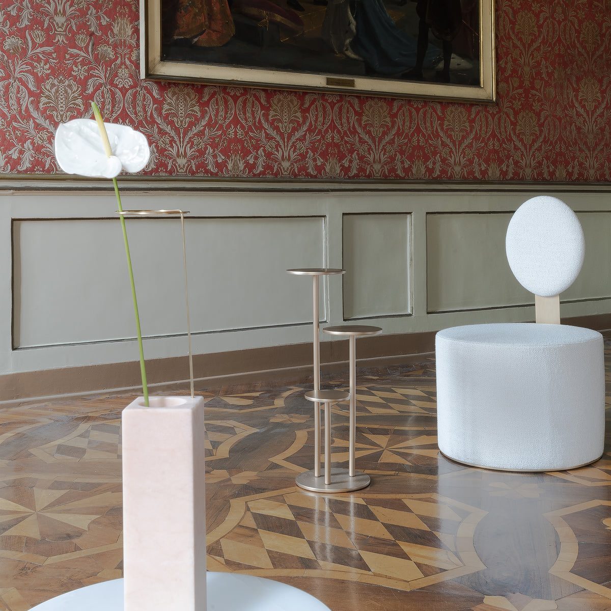 Orion Side Table beside a white chair and anthurium vase on a parquet floor