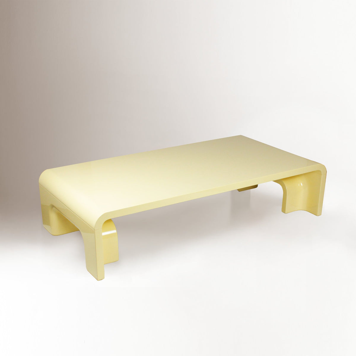 Plié Centre Table in Sand Yellow lacquer, three-quarter view of low curved-leg table