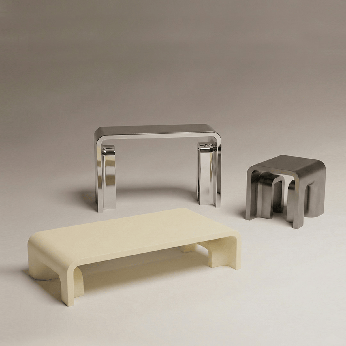 Plié Console in Polished Inox with a cream coffee table and steel side table
