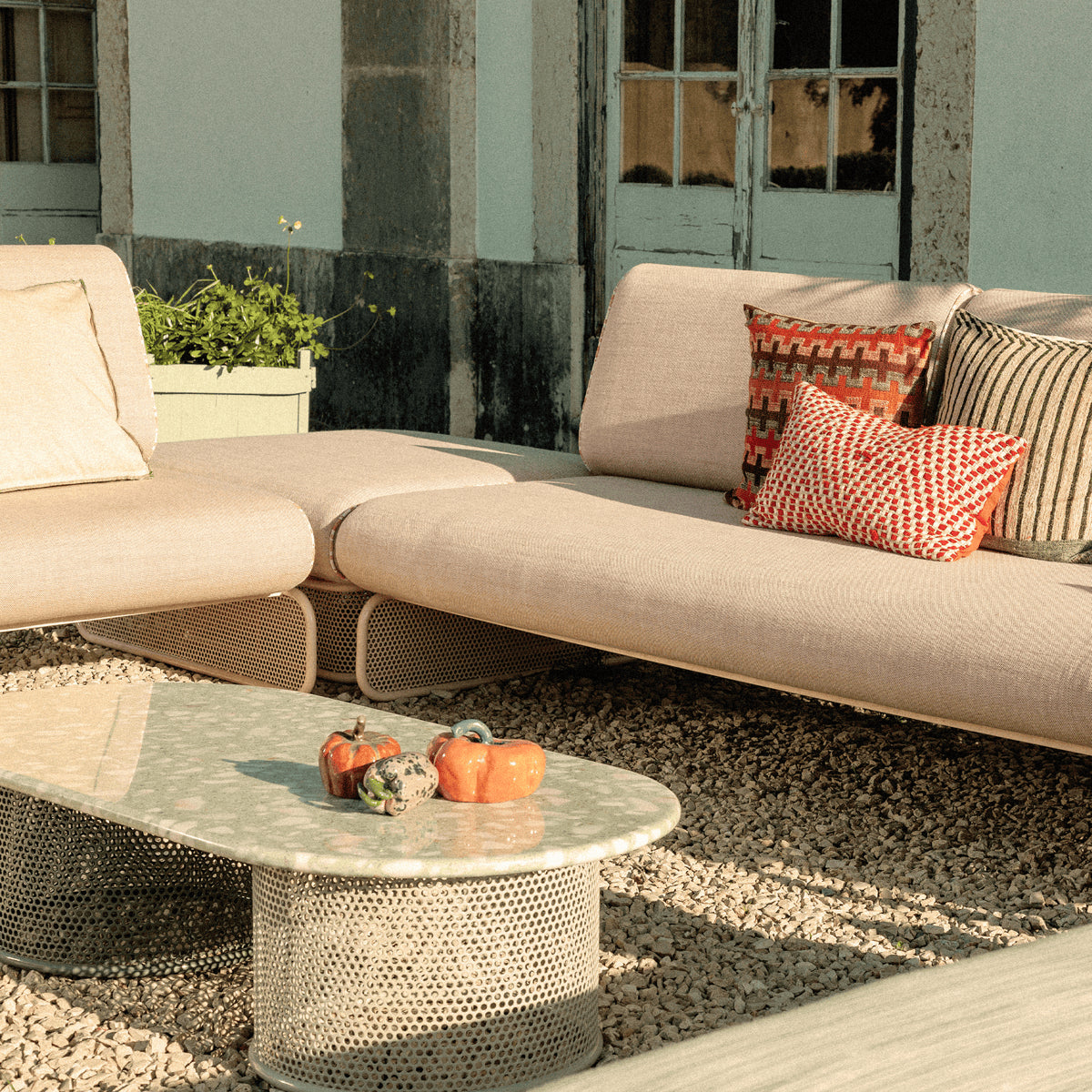 Riviera Coffee Table on gravel beside an outdoor lounge sofa with cushions