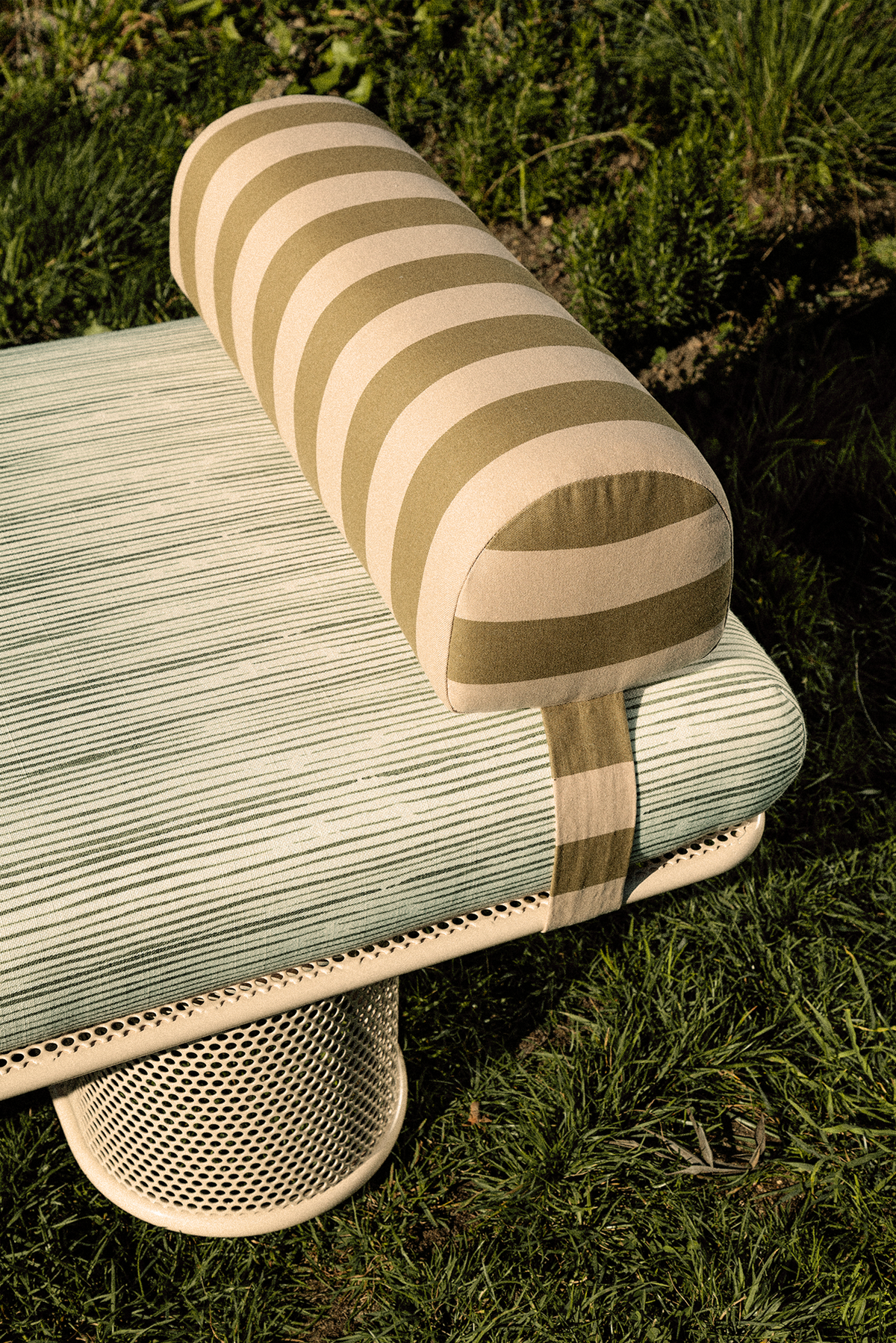 Riviera Bench close-up of striped bolster and cushion on the lawn