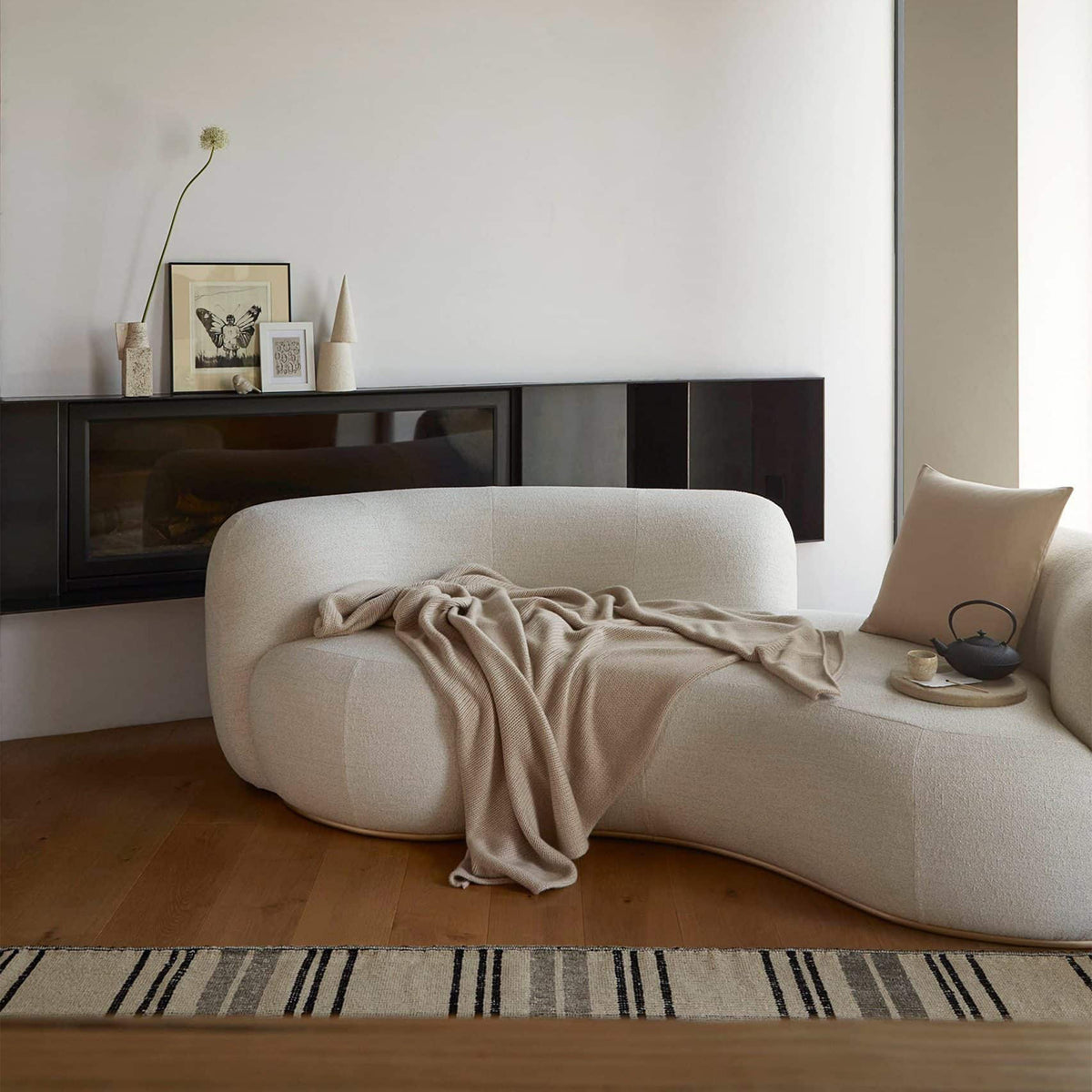 Tateyama Cloud Sofa in ivory bouclé with knit throw below a fireplace console