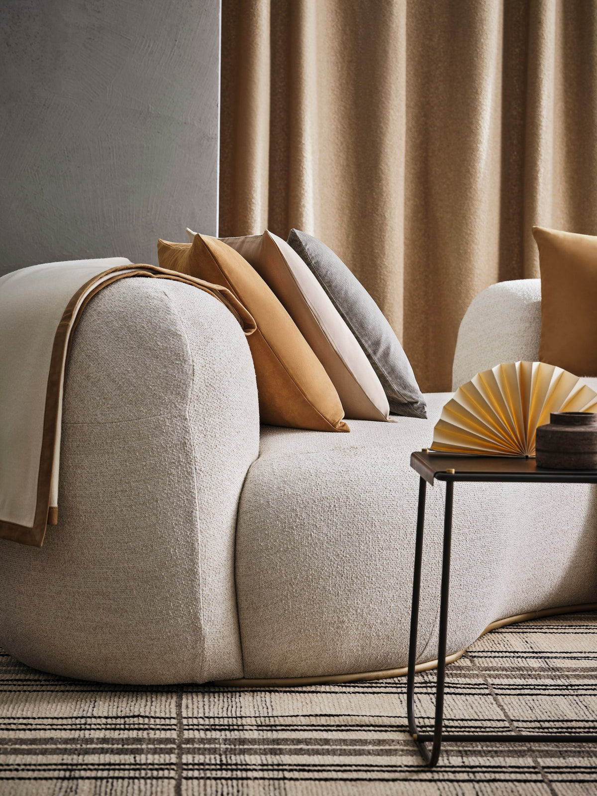 Tateyama Cloud Sofa close-up of the rounded arm with tan pillows and side table
