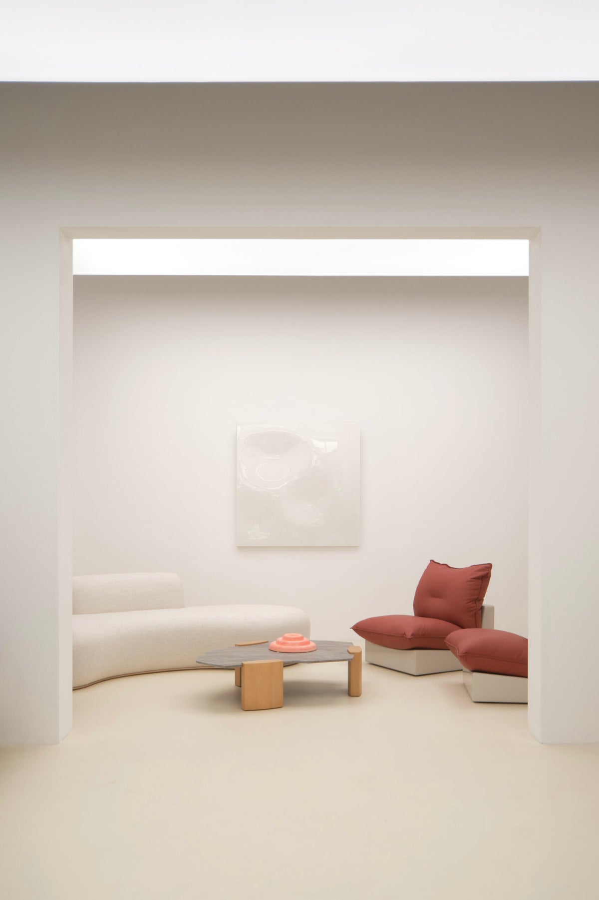 Tateyama XL Sofa in cream with red cushions and a low wood table in a minimal room