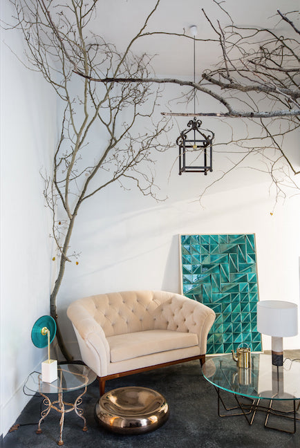 Tejo Panel in Jade leaning beside a tufted armchair and branches