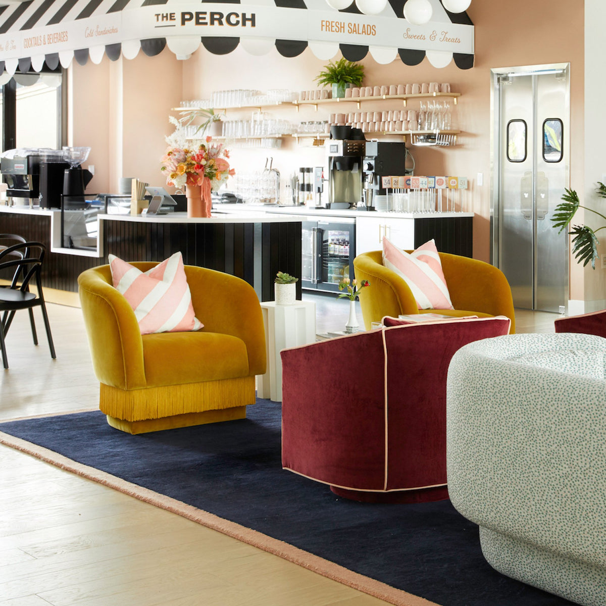 La Folie Armchairs in mustard velvet with striped pillows in a café lounge