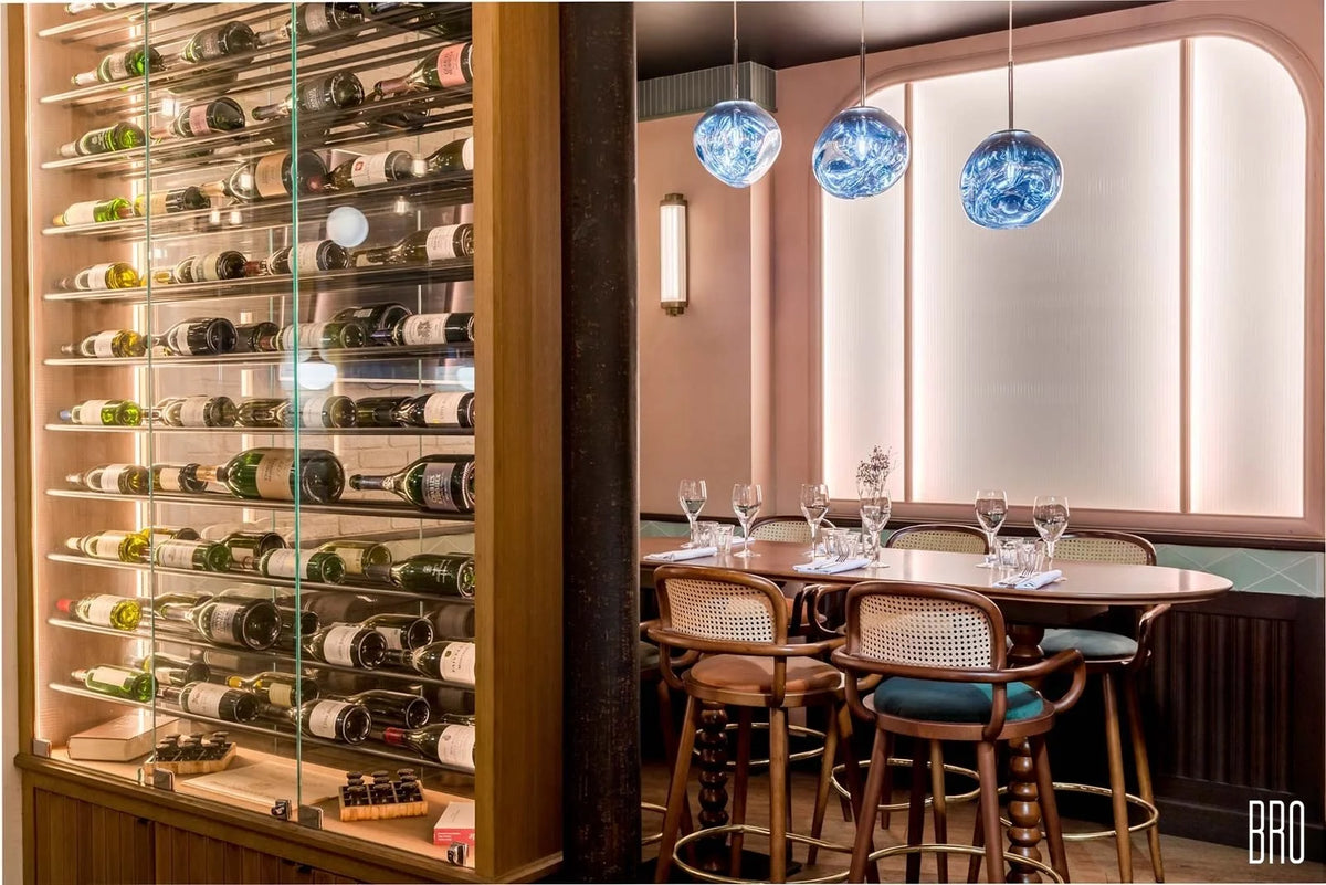 Luc bar chairs at a high table beside a glass wine wall