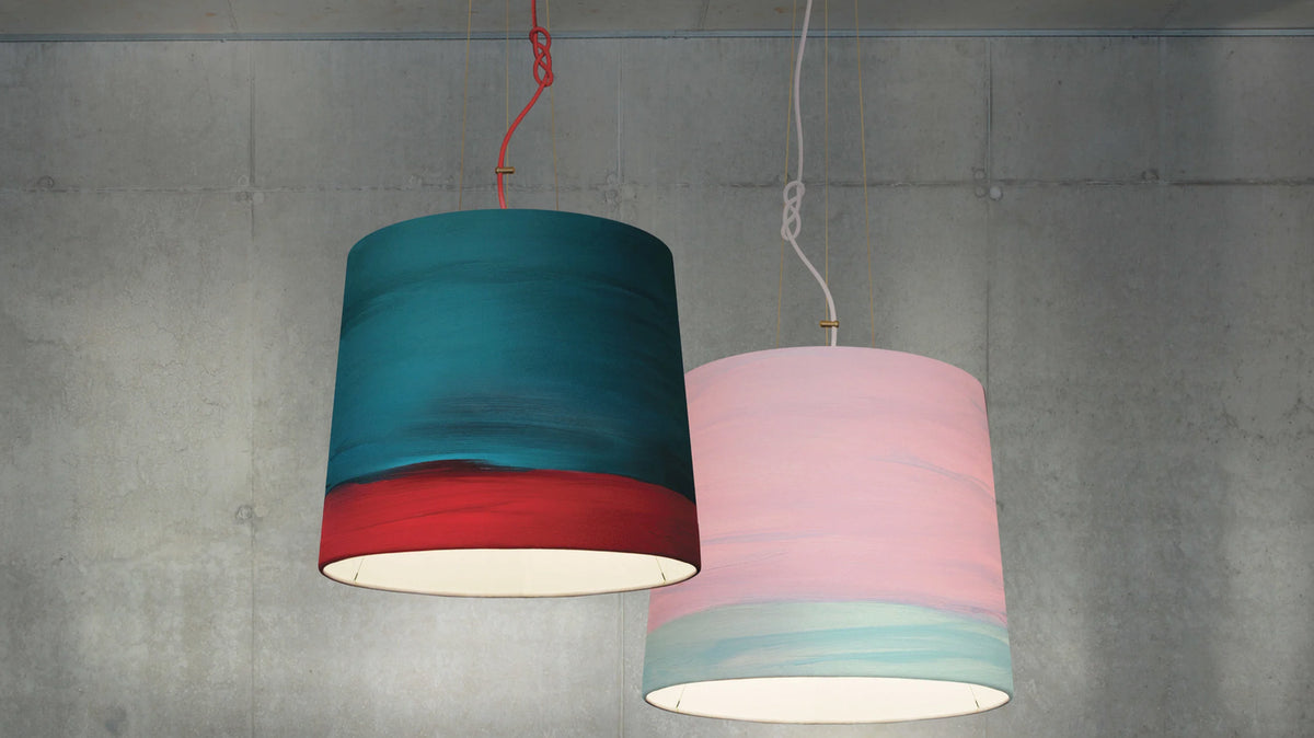 Teal and pink drum pendant lights against a concrete wall