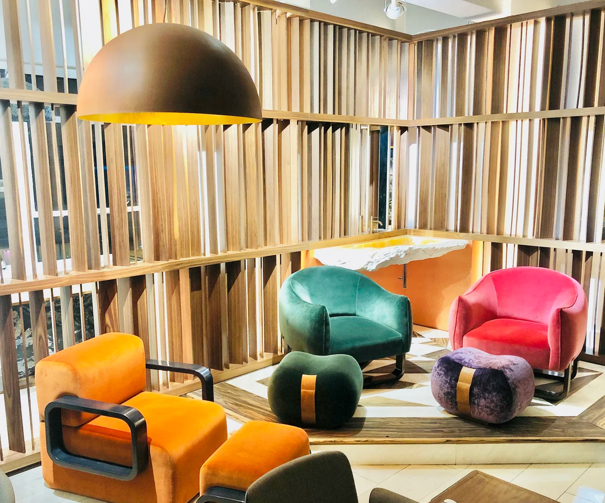 Colourful velvet armchairs and poufs in a room lined with wood shelves