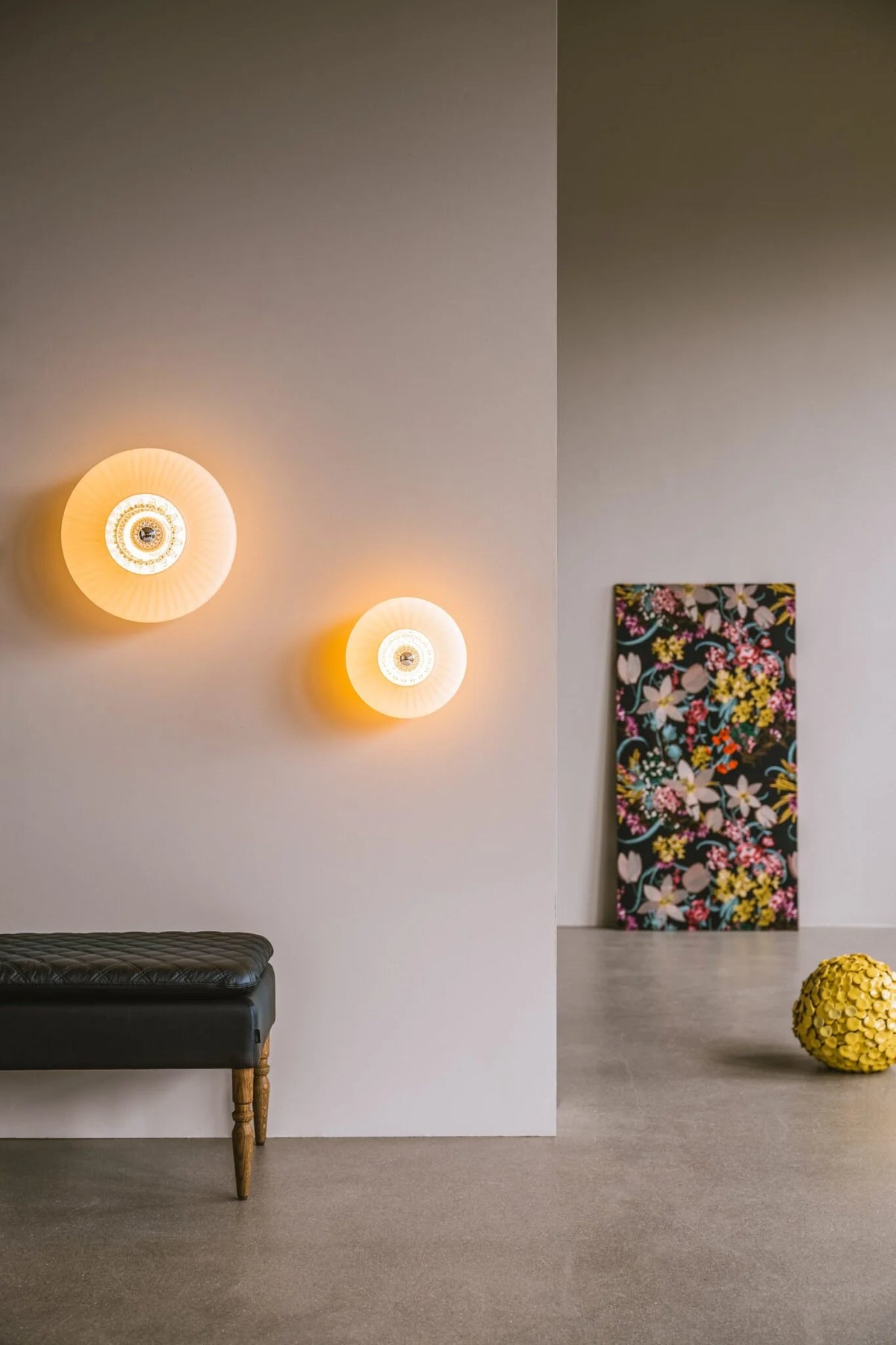 Two glowing round wall sconces above a black bench