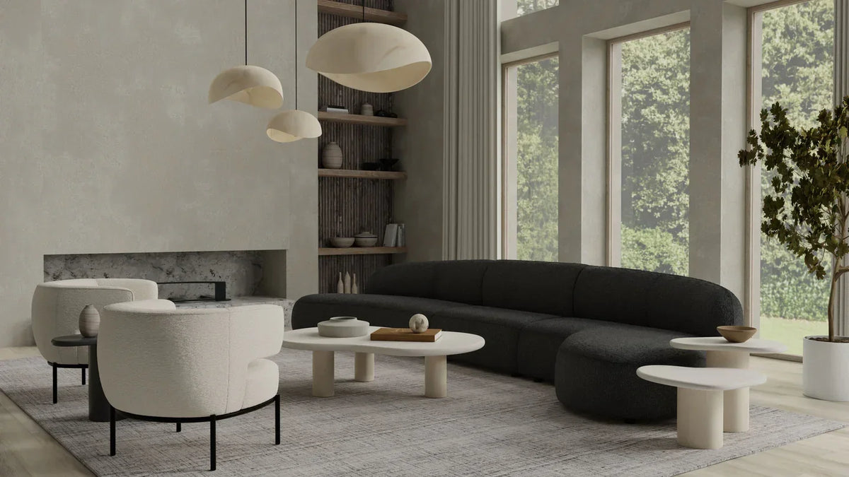 Living room with a black curved sofa, cream armchairs and paper pendants