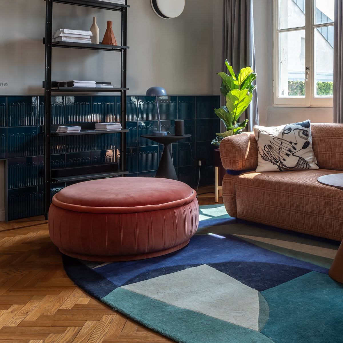 Malibu Ottoman in terracotta velvet on a blue rug in a living room