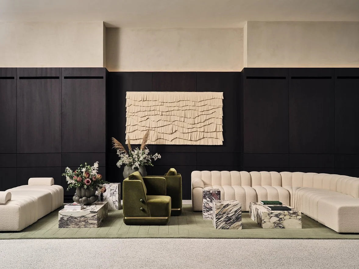 Panorama Armchair in green velvet in a lounge with a cream modular sofa and marble tables