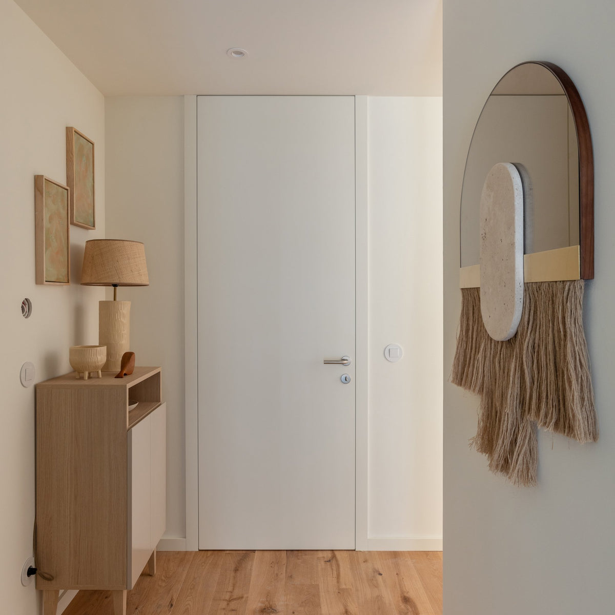 Souk Ecru Mirror Shell hung in a hallway beside a wood console and lamp