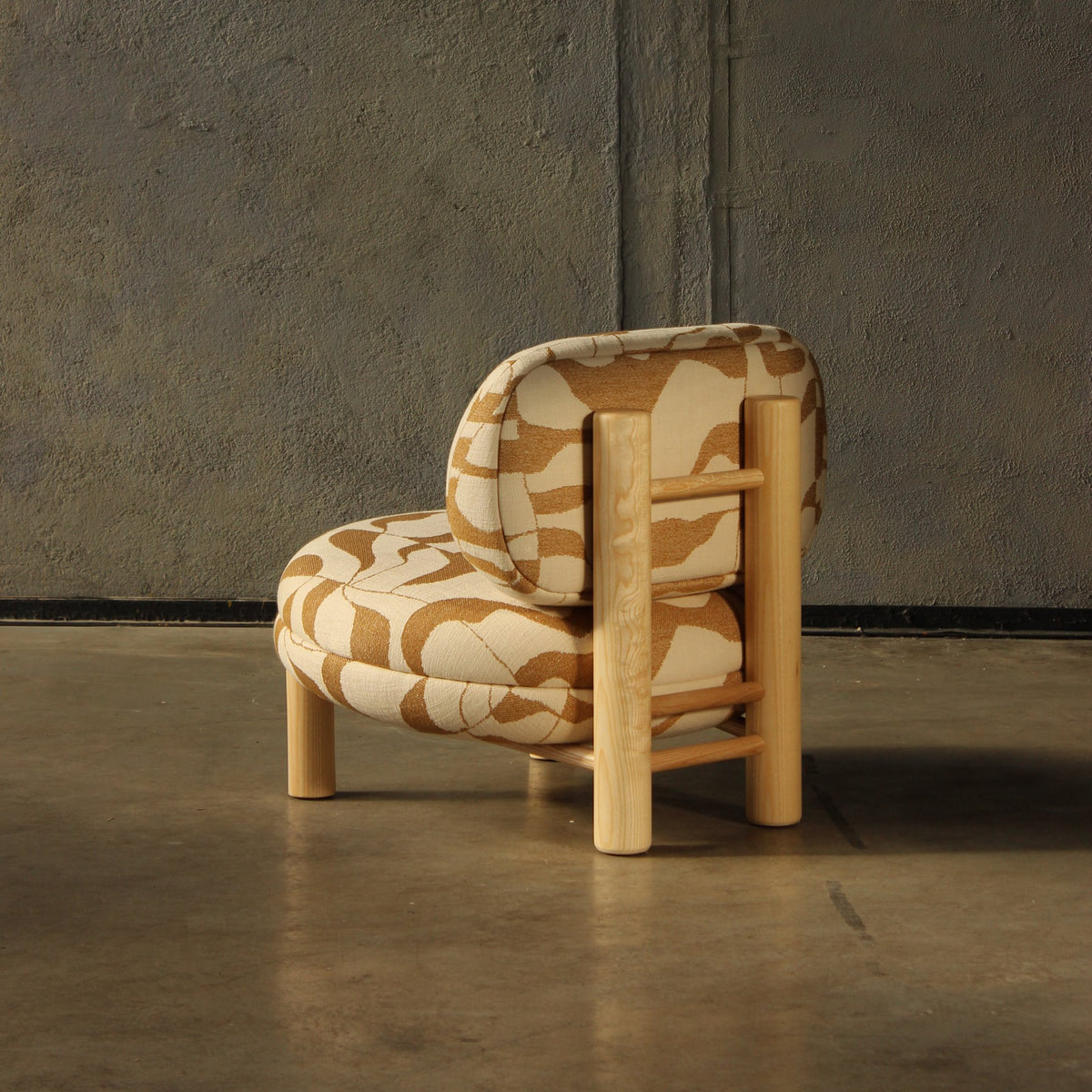 Aimi Lounge Chair in cream and terracotta pattern, rear view on a polished concrete floor