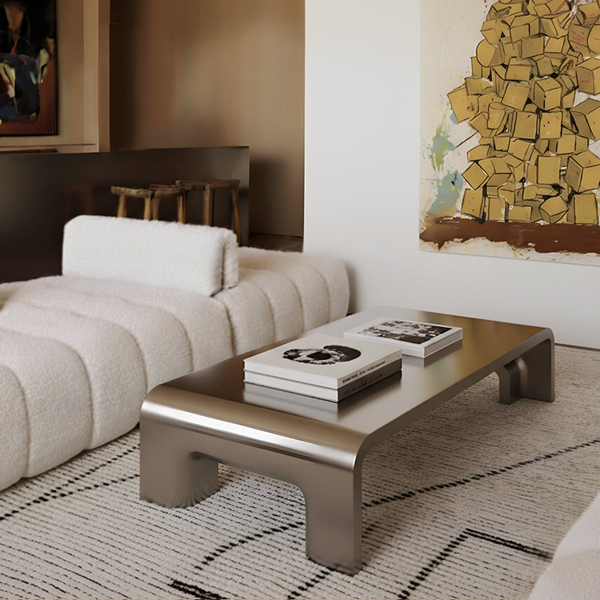 Plié Centre Table in brushed metallic finish in front of a white channelled sofa