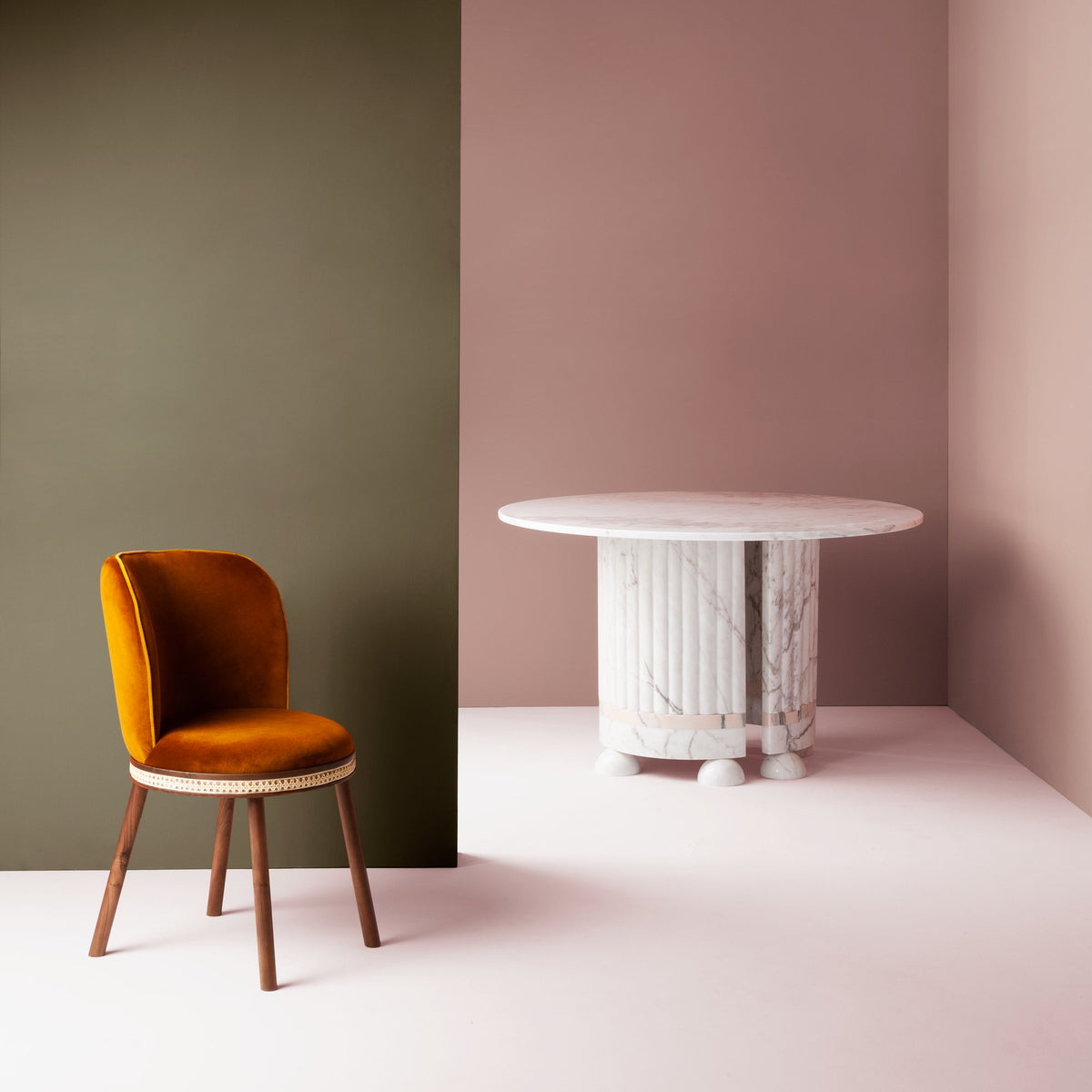 Alma Dining Chair in rust velvet beside a white marble round table