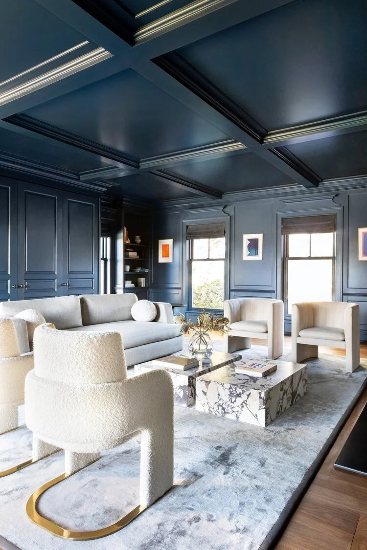 Odisseia Dining Chair in white bouclé in a navy-panelled living room with a marble coffee table