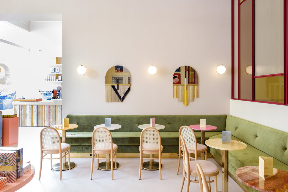 Souk Mirror Black on a café wall above a green banquette, wide view
