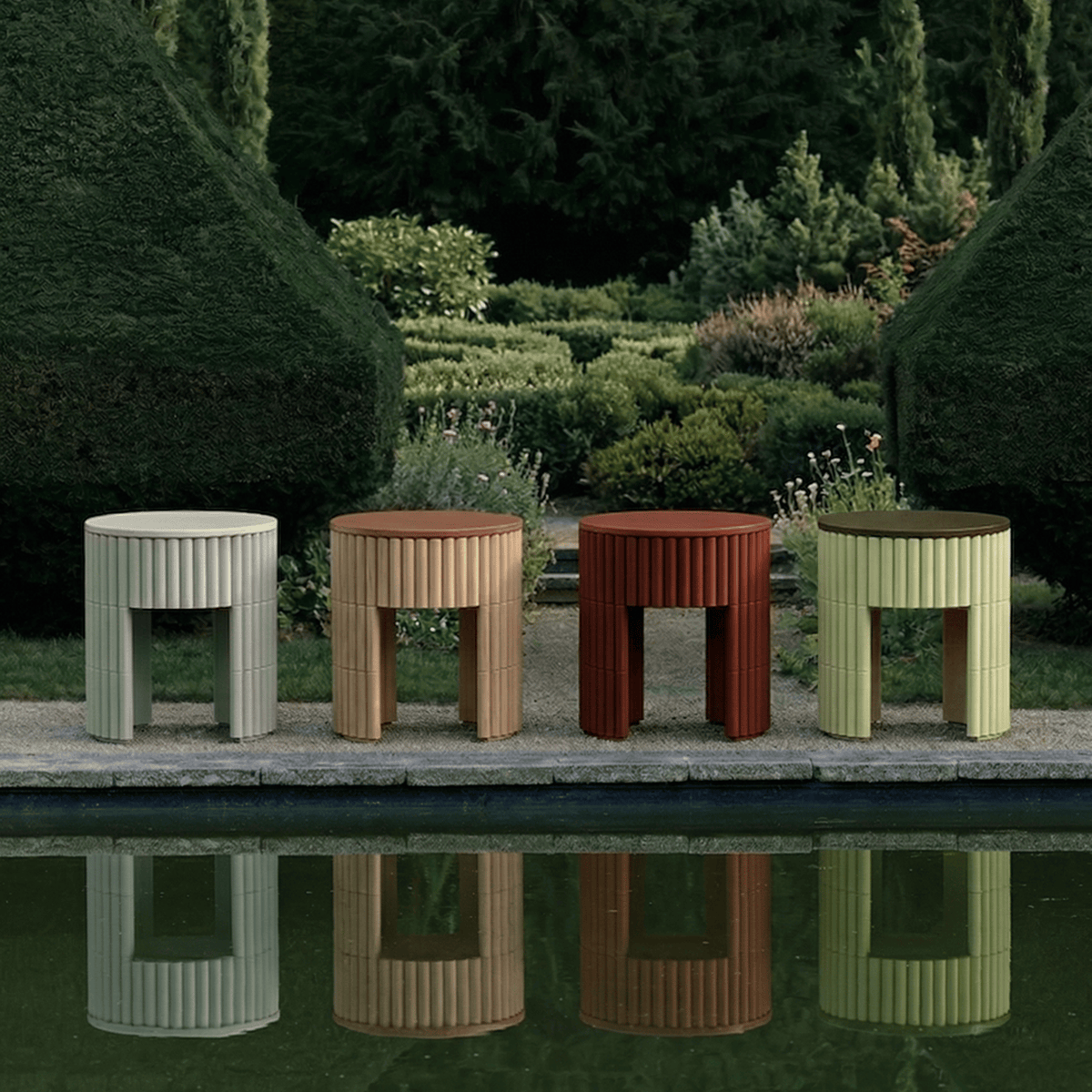 Nouvelle Vague Side Tables in four colours lined up beside a garden pool