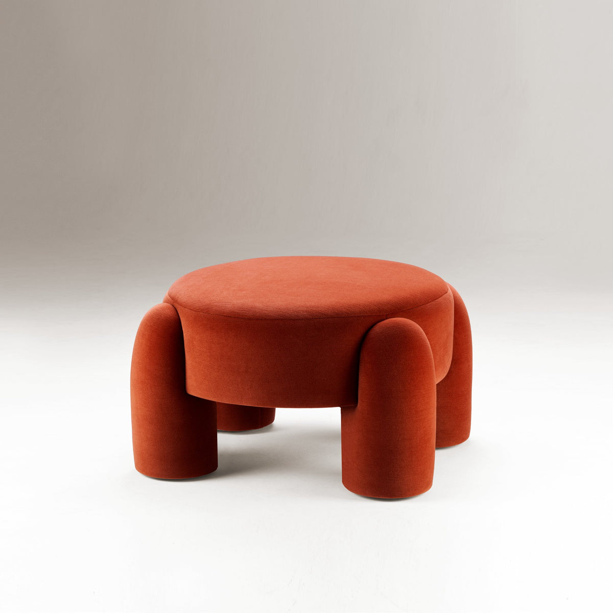Marlon Pouf in rust red on a grey backdrop