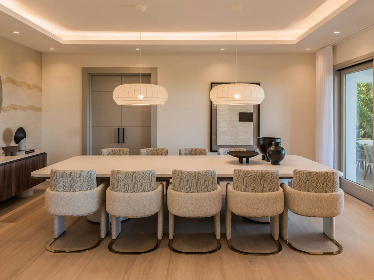 Odisseia Dining Chairs in neutral fabric around a long marble dining table in a modern dining room
