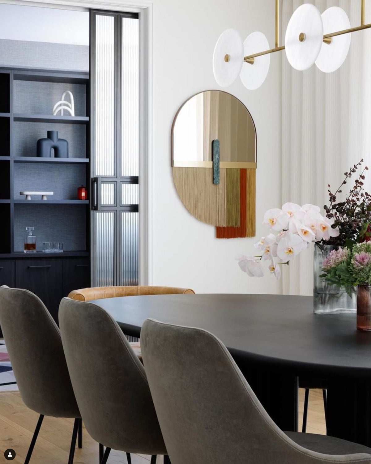 Souk Mirror Red in a dining room with orchids and a pendant light