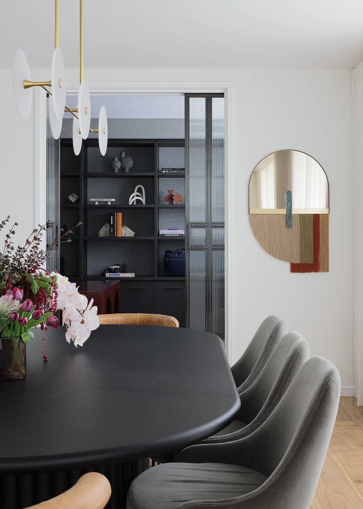 Souk Mirror Red above a black dining table with grey chairs