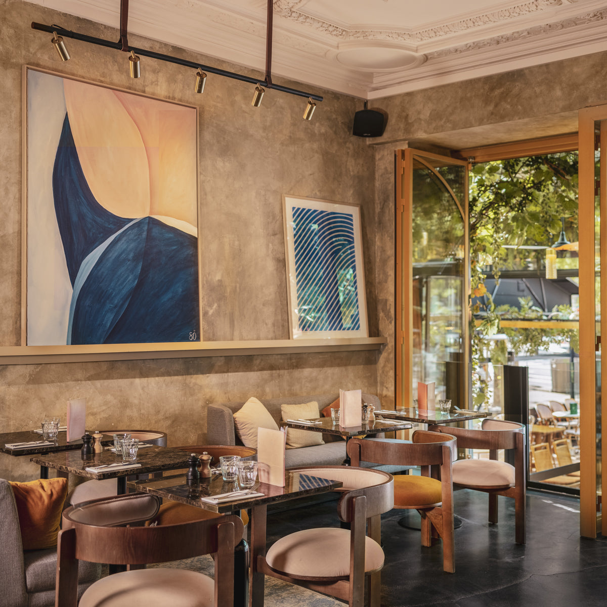 Moulin Dining Chairs in a restaurant with abstract wall art and an open terrace