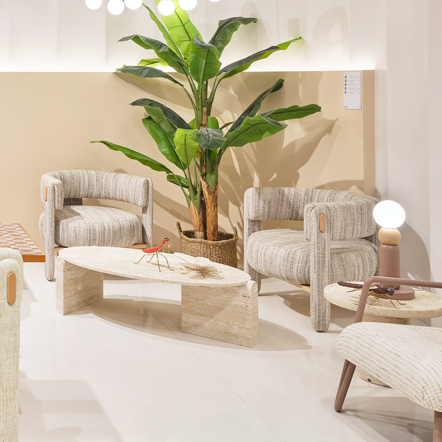 Choux Armchair pair in striped weave beside a travertine coffee table and banana plant